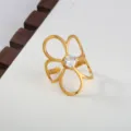 Gedetailleerd aanzicht van een stijlvolle roestvrijstalen bloemring met een zirkoon. - Vierblads Bloemstijl / Goud