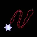 Close-up of a glowing snowflake pendant necklace with red beaded chain for Christmas party. - Snowflake Necklace