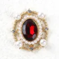 Primo piano dettaglio vintage barocco ovale rosso gemma perla lega spilla DIY gioiello base. - Rosso scuro