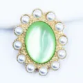 Detalle de cerca de piedra de ojo de gato verde vintage con borde de perlas accesorio DIY. - Verde claro