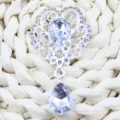 Detailed close-up of a silver alloy rhinestone flower pendant with a clear crystal drop. - White