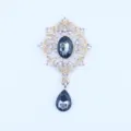 Detail van gouden legering hanger met strass-steentjes en donkere druppelvormige kristalstenen. - Grijs