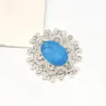 Detailaufnahme eines ovalen blauen Harz Kristall Strass Legierung Blumenknopf DIY Schmuck. - Seeblau