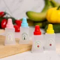 Vista detallada de mini botellas de plástico flexibles con tapones de colores para bento. - Set de 4 Botellas de Condimento Cuadradas