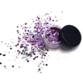 Detailed view of sparkling purple holographic cosmetic glitter in small jar with scattered flakes. - Mixed Purple