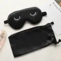 Black silk sleep mask with cute embroidered eyelashes, matching storage pouch for travel. - Black
