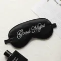 Black silk embroidered sleep mask with adjustable strap and Good Night text for travel rest. - Black