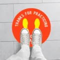 Round social distancing warning floor sticker with yellow footprints and English text. - XG018 5 Sheets