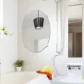 Bathroom detail view showing an elegant oval wall decorative mirror mounted on the wall. - JM709