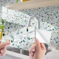 Terrazzo pattern crystal film tile sticker detail shot showing self-adhesive backing peel. - DLS124