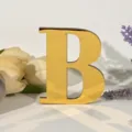 Close-up van gouden acryl letter B decoratie met bloemige rekwisieten voor binneninterieur. - Letter B / Goud
