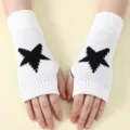 Detail shot of winter knitted fingerless gloves with black star pattern on white fabric. - White