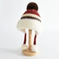 Vue detaillee de la garniture en peluche duveteuse et de la texture tricotee du bonnet enfant. - Taille unique / Rouge