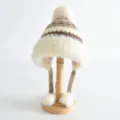 Gros plan sur la texture du bonnet d'hiver pour enfant en tricot avec pompon doux et cache-oreilles. - Taille unique / Kaki