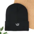 Black knitted beanie hat with white embroidered crown motif, cozy winter warm pull-on wool cap style. - Crown Embroidered Beanie - Black