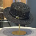 Detailed shot of a black hollow straw flat top sun hat with leather strap and metal loops. - Black Hollow Straw Hat with Belt