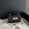 Zwarte glinsterende schoudertas met gouden ketting en metalen draaisluiting voor dames. - Zwart