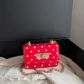 Rode lakleren schoudertas met witte stippen, gouden ketting en chique draaisluiting. - Rood met stippen