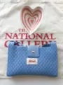 Close-up of blue knitted crossbody bag with diamond pattern, magnetic snap closure, and label. - Sky Blue