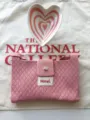 Detailed view of a pink knit crossbody mini bag, featuring a snap button and textured fabric. - Pink