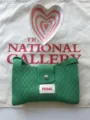Detail view of the green knit crossbody bag, featuring textured fabric and secure snap button. - Green