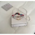 White ostrich pattern Kelly handbag detail showcasing structured design and metal hardware. - White