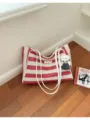 Vue détaillée d'un sac cabas rayé rouge et blanc avec des bretelles blanches et un pendentif. - Style Tote / Rouge avec pendentif