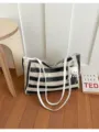 Détail du sac cabas en paille rayé noir et blanc, avec lanières blanches et joli pendentif. - Style Tote / Noir Avec Pendentif