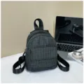 Detailed shot of a black and white grid mini backpack placed on a clean white desk with props. - Black and White Grid Style / Black