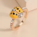 Nahaufnahme Detail des eleganten Marienkäfer Strass Rings in Roségold mit funkelnden Kristallen. - Größe 6 / Gelb