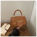 Chique bruine zadelzak voor dames, elegante schoudertas met stijlvol metalen accent. - Bruin