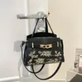 Black women handbag with gold embroidery and metal lock design, elegant crossbody shoulder bag. - Black