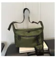 Detail view of the green nylon crossbody bag showcasing durable zippers, D-ring and utility strap. - Green
