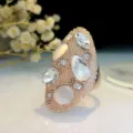 Close-up detail van een vintage roségouden statement langring met kristallen en kattenogen. - Maat 6 / Witte edelsteen