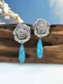 Primo piano dettagliato di orecchini rosa argento retro con ciondolo turchese blu. - Stile Goccia d'Acqua Turchese Blu / Argento