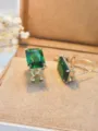 Primo piano dettagliato di orecchini di lusso con pietre preziose verdi quadrate ed eleganti. - Pietra verde / Oro