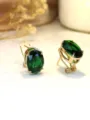 Primo piano dettagliato di orecchini pendenti con gemma verde ovale e montatura dorata. - KC Oro Verde