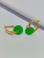 Primo piano di orecchini a cerchio dorati ritorti con pendenti in pietra verde. - Verde