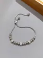 Primo piano di un bracciale a catena di serpente argento con perline e distanziatori strass. - Stile perla rotonda liscia / Perline argentate