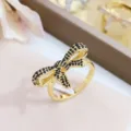 Gros plan détaillé d'une bague nœud dorée délicate incrustée de zircons noirs scintillants. - Taille unique / Or Avec Zirconia Noir