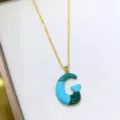 Primo piano di una collana con ciondolo lettera colorblock dopamina su vassoio, chic. - Lettera G