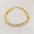Vista di dettaglio di un bracciale a farfalla dorato decorato con zirconi quadrati lucidi. - Rettangolo Bianco