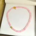 Primo piano dettaglio collana di perline in pietra naturale rosa con chiusura dorata. - Perlina rotonda rosa