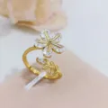 Anello aperto dorato con dettagli floreali e di foglie in zircone cubico, macro scatto. - Grano di Fiore (Oro)