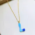 Primo piano dettagliato della collana con ciondolo lettera L in smalto con catena dorata. - Taglia L