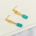 Primo piano dettagliato di orecchini a catena dorati con bellissimi pendenti in pietra turchese. - Turchese