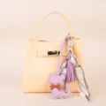 Detailed view of elegant yellow handbag featuring a cute purple cat charm and silk scarf. - Purple Tassel Scarf and Purple Kitten