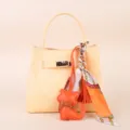 Elegant yellow leather handbag with chic printed silk scarf and cute orange cat charm pendant. - Orange Tassel Scarf and Orange Kitten