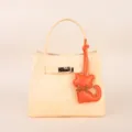 Detailed view of pale yellow leather handbag with metal lock and cute orange cat pendant charm. - BHT07 Orange Kitten