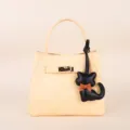 Detailed view of the beige leather handbag featuring a metal turn-lock closure and cat charm. - BHT07 Black Kitten